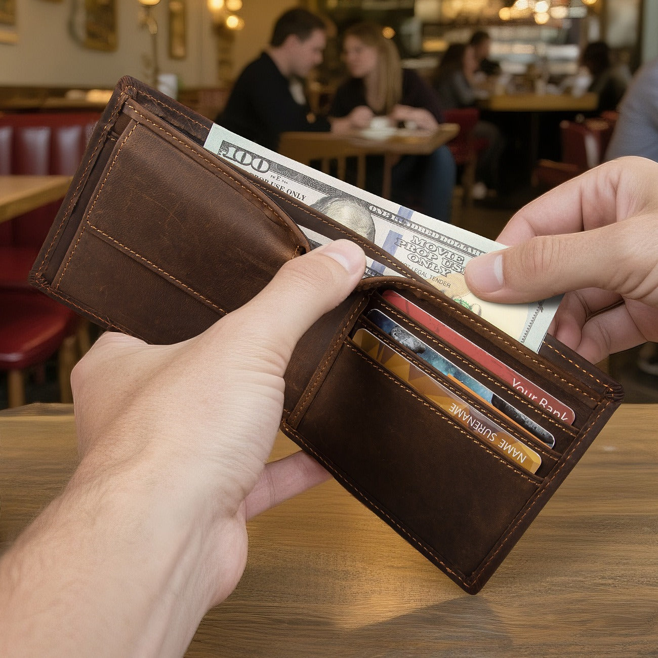 Man holding open a dark brown men's wallet at a cafe