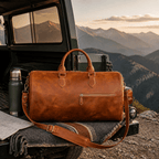 Brown men's carry-on bag on a truck bed with mountain view