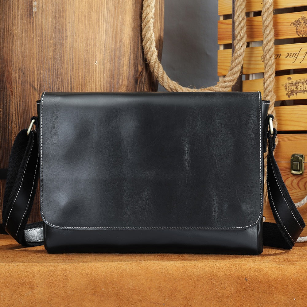 Black men's leather messenger bag on a wooden barrel