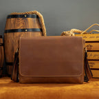 Brown men's messenger bag on a wooden barrel, front view