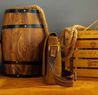Brown men's messenger bag on a wooden barrel, side view