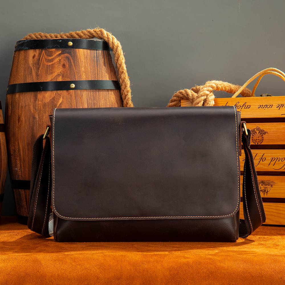 Dark brown men's messenger bag on a wooden barrel
